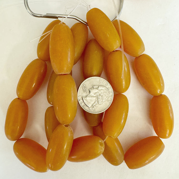 faux amber resin, pale dark yellow orange, 29x15mm bowed tube, 7pc strand, sold per strand