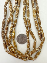 golden brown off white, eye motif, vintage stock bone, 24x6mm bowed tube, 15" strand, sold per strand