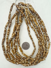 golden brown off white, eye motif, vintage stock bone, 24x6mm bowed tube, 15" strand, sold per strand