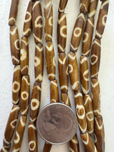 golden brown off white, eye motif, vintage stock bone, 24x6mm bowed tube, 15" strand, SOLD PER STRAND